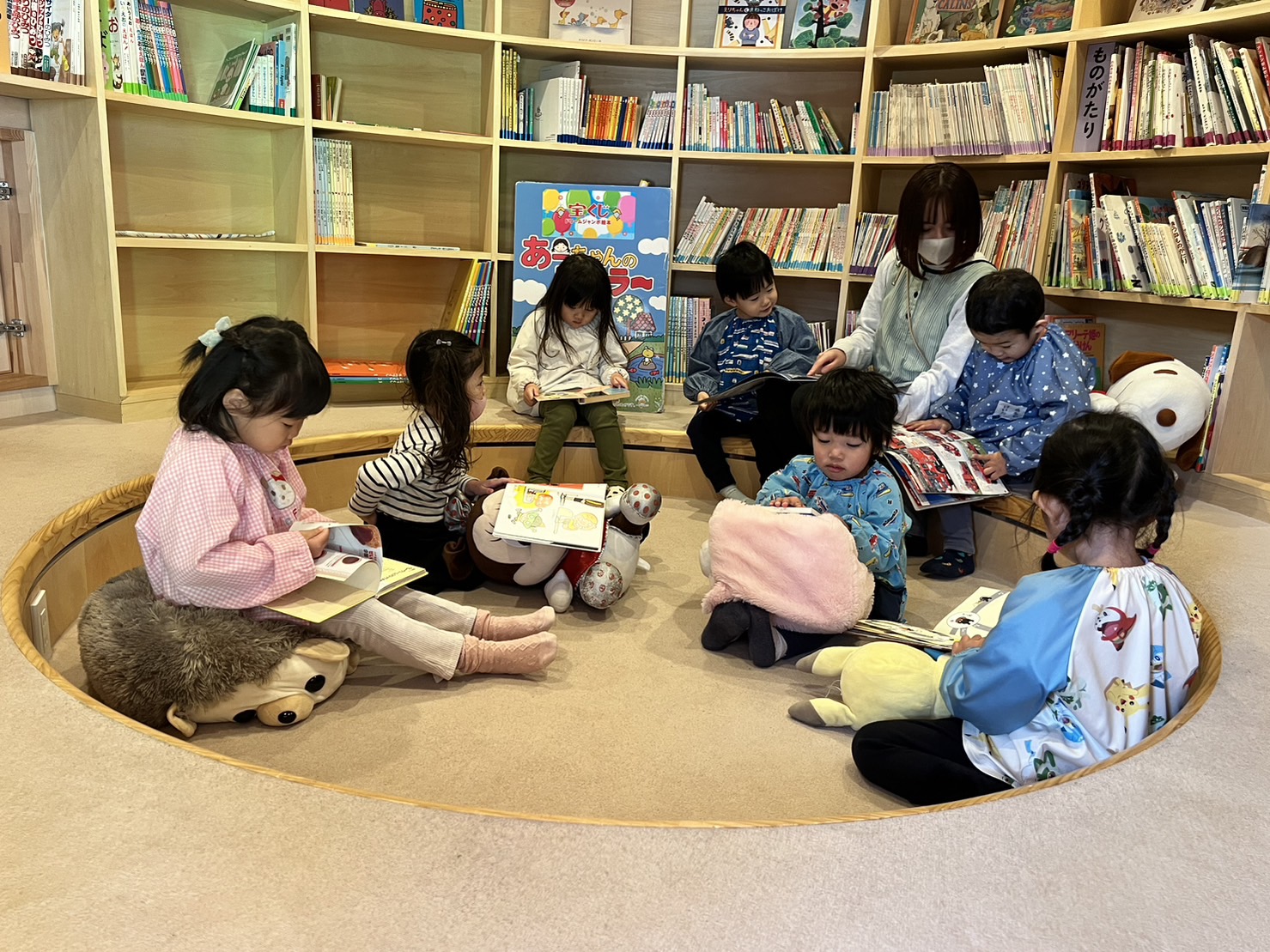 子どもたちがぬいぐるみに座って本を読んでいる